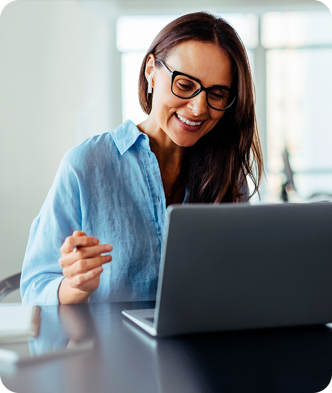 Mulher em sua mesa de trabalho olhando para a tela do notebook em sua frente Mulher em sua mesa de trabalho olhando para a tela do notebook em sua frente