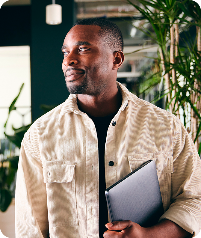 Homem no escritório segurando um notebook e sorrindo Homem no escritório segurando um notebook e sorrindo