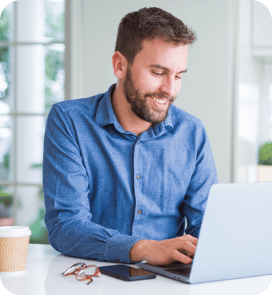 Homem sorrindo e trabalhando no computador.